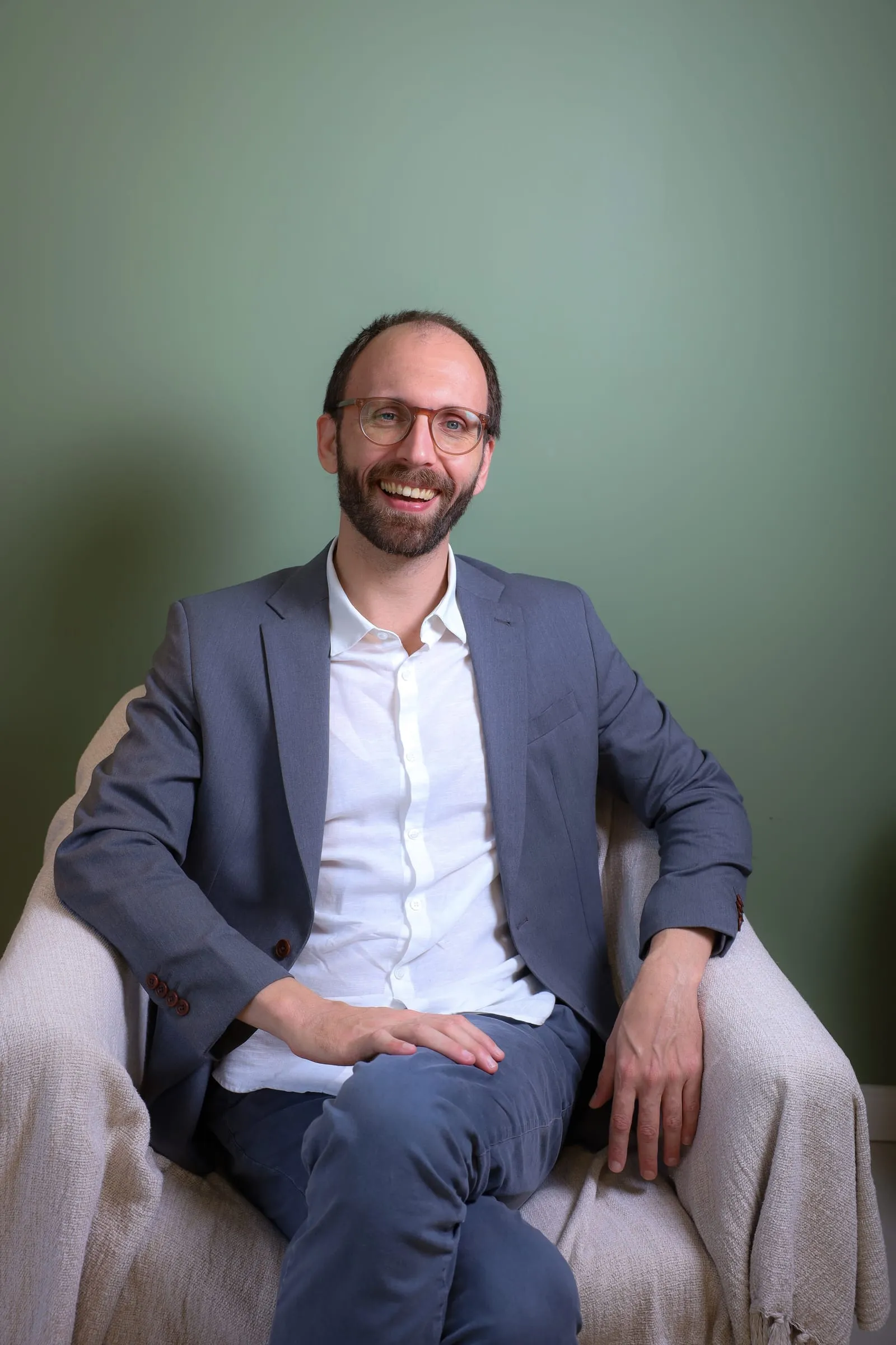 Dr. Roberto Gimena smiling in an armchair in his office