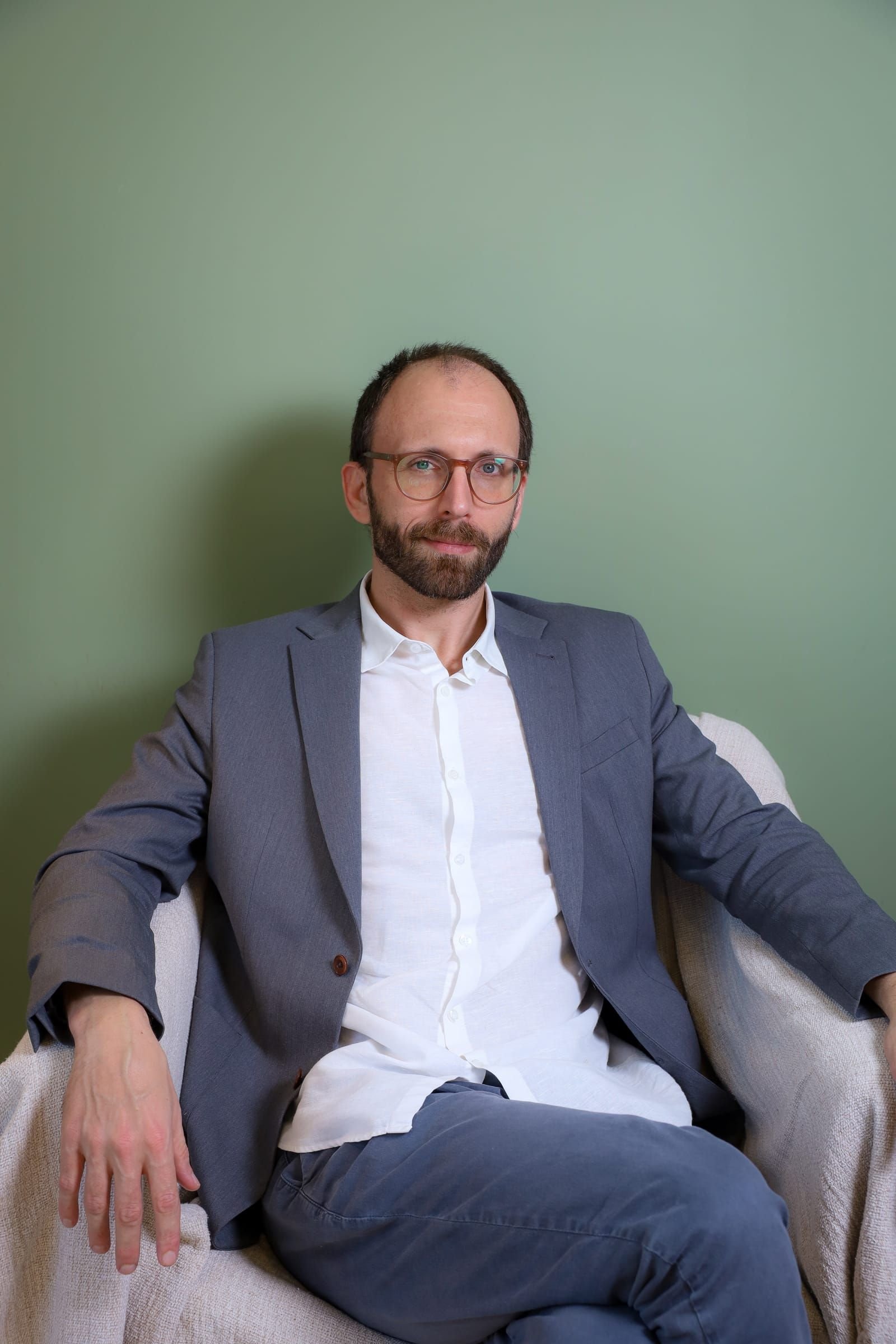 Dr. Roberto Gimena sentado numa poltrona do consultório, olhando para a câmera