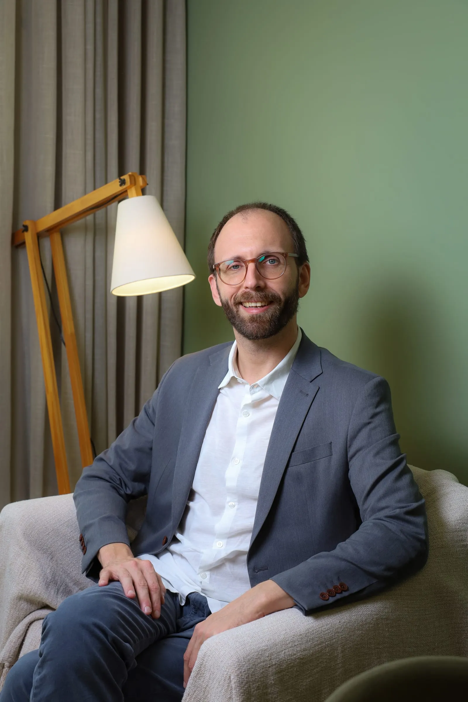 Dr. Roberto Gimena sorrindo na poltrona do consultório, ao lado da luminária