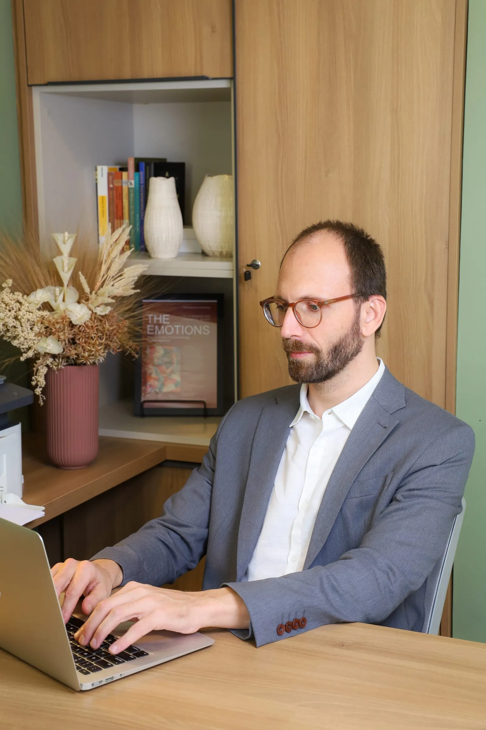 Dr. Roberto Gimena trabalhando no notebook, à mesa do consultório