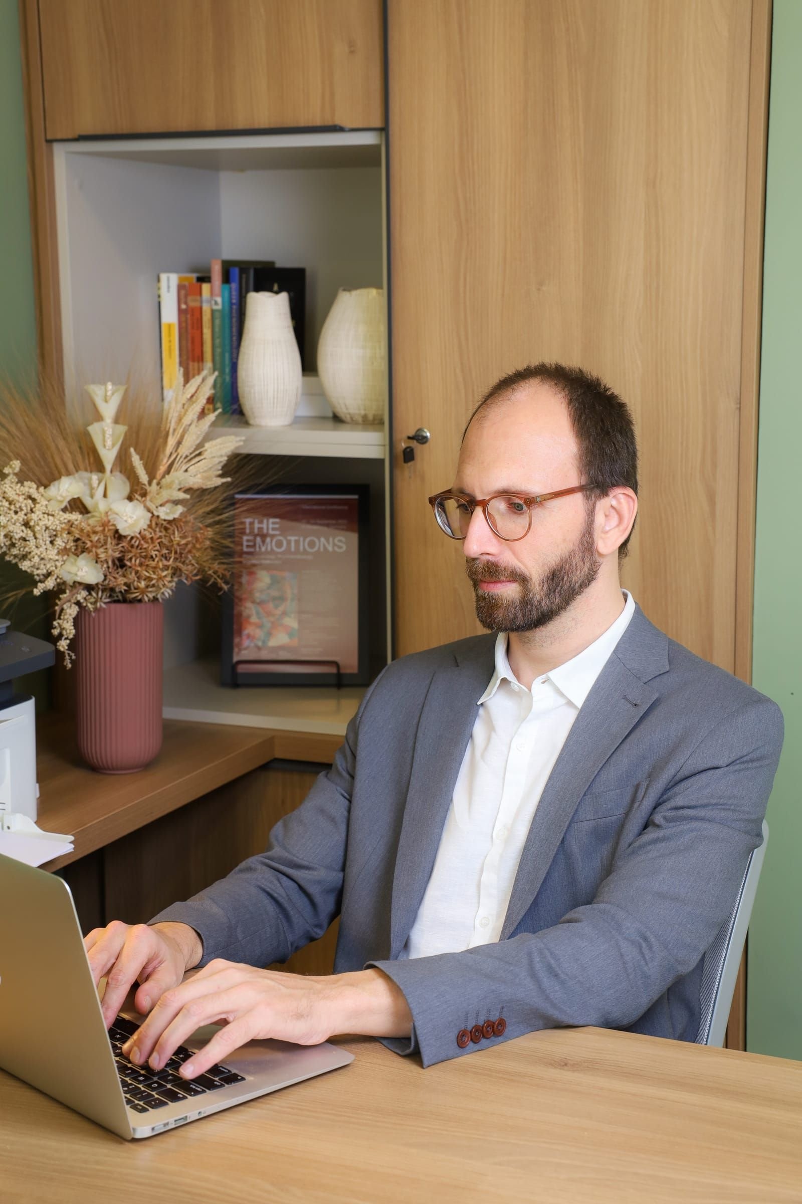 Dr. Roberto Gimena trabalhando no notebook, à mesa do consultório