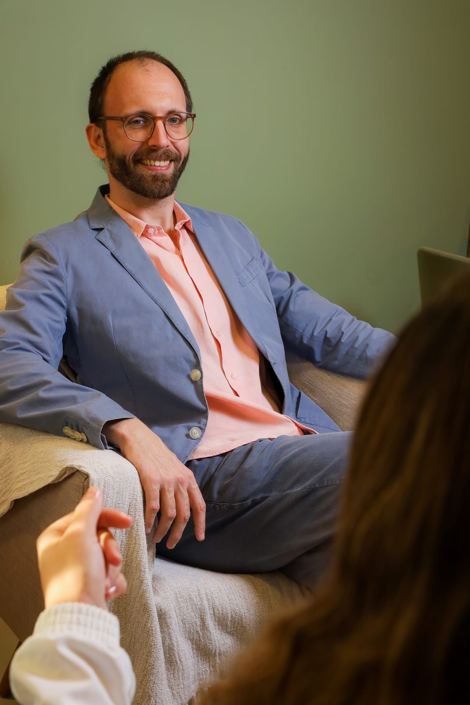 Dr. Roberto Gimena sorrindo na poltrona durante uma consulta, com a paciente de costas em primeiro plano