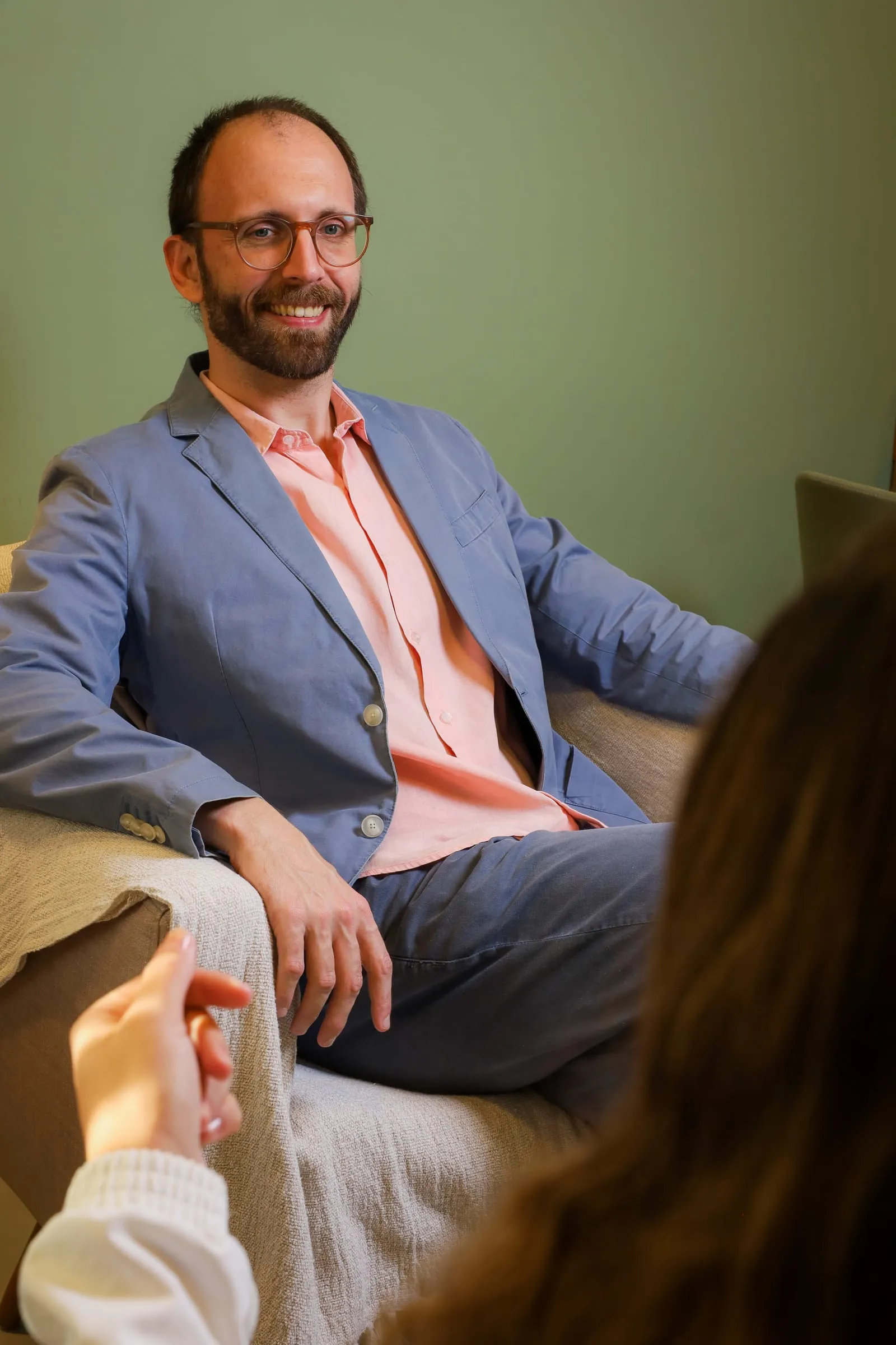 Dr. Roberto Gimena sorrindo durante uma consulta, com o paciente de costas