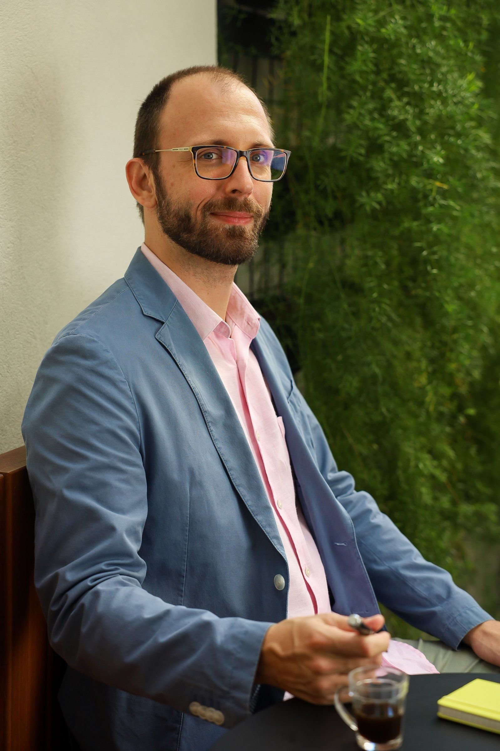 Dr. Roberto Gimena com café diante de um jardim vertical