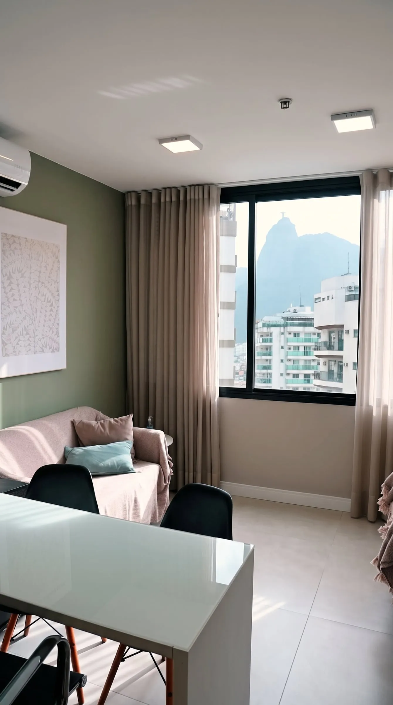 Segunda sala, com mesa branca, sofá e a janela com vista para o Cristo Redentor