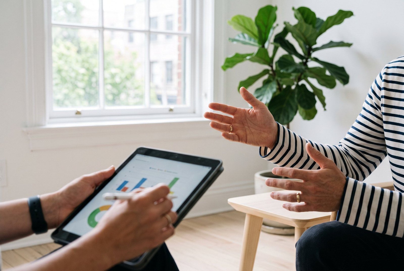 Duas pessoas conversando; uma delas segura um tablet com um gráfico